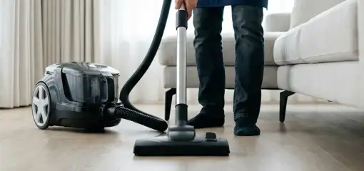 Professional house cleaner vacuuming a living room floor with a canister vacuum cleaner, Las Vegas, NV.
